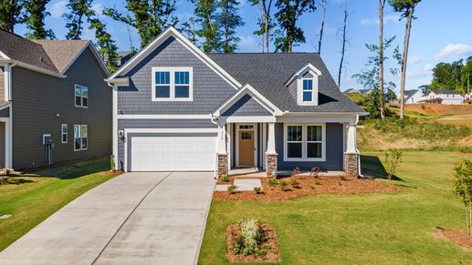 Dark blue exterior home with two car garage, covered front porch, and stone columns with yellow front door at Pelham Crossing