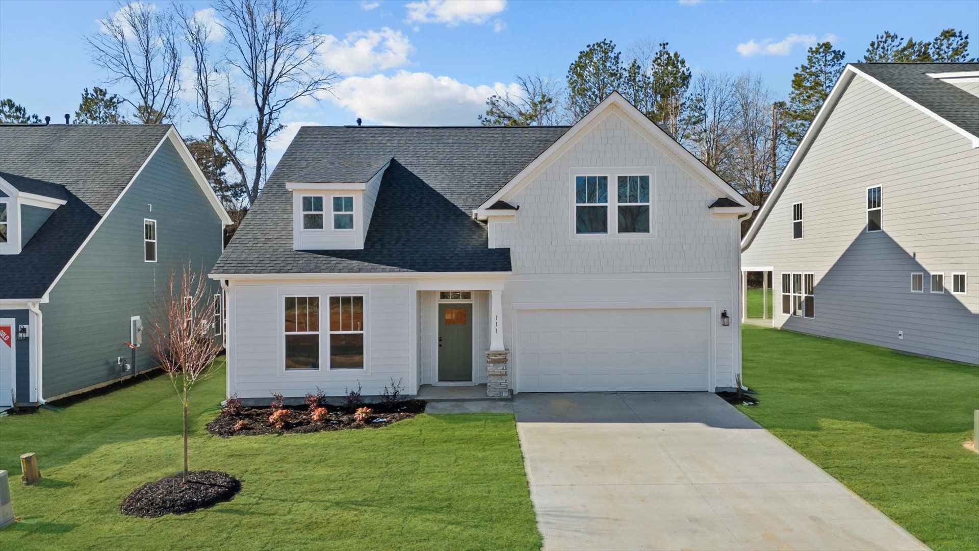 Stunning, bright, white exterior ranch style home with two car garage and stone columns at Pelham Crossing by DRB Homes