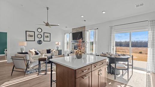 Open concept living spaces with large family room with fireplace and adjacent wood cabinetry kitchen in Greenville, SC