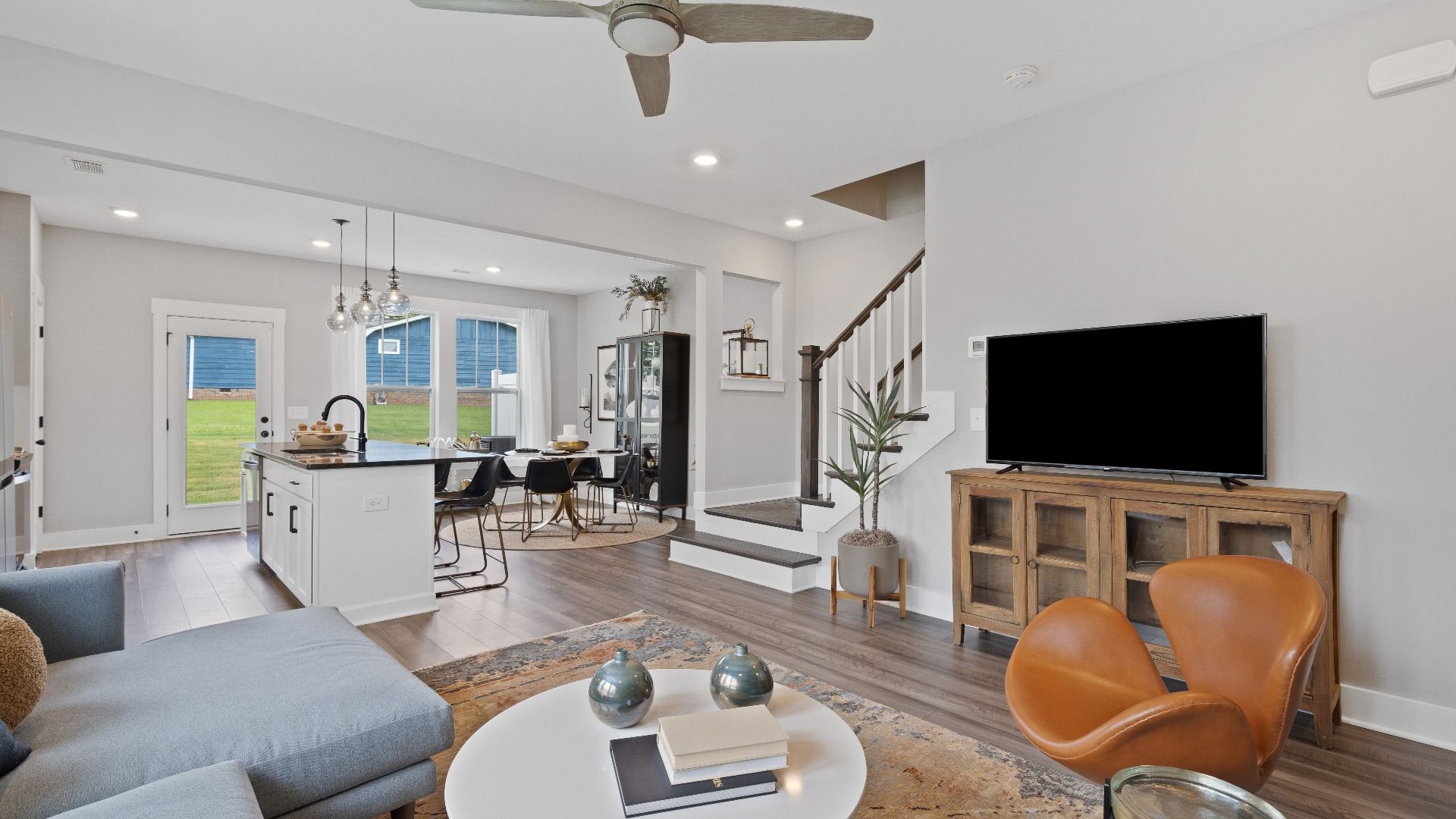 Spacious hardwood flooring family room with large windows and ceiling fan at Barton Hollow by DRB Homes in Fountain Inn, SC
