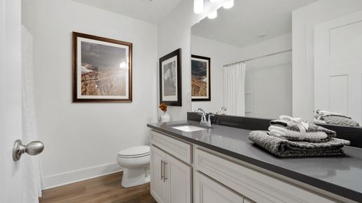 Black granite countertopped large vanity with white cabinetry at Barton Hollow by DRB Homes in Fountain Inn, SC