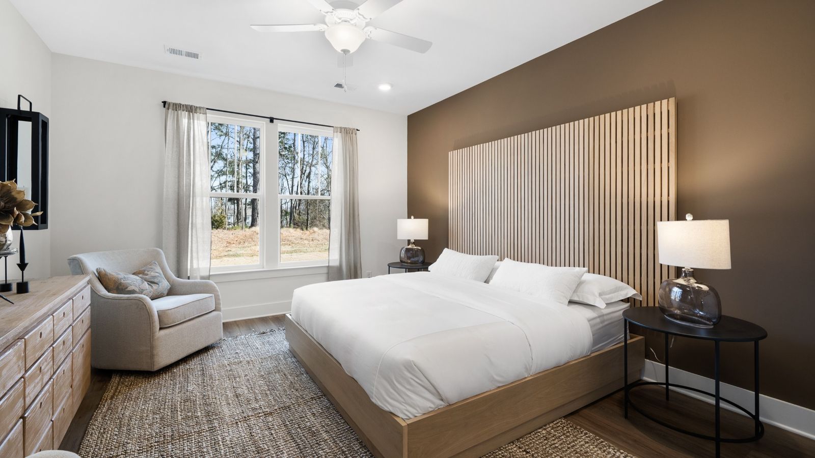 Cozy primary suite with large windows, ceiling fan, and hardwood flooring at Barton Hollow by DRB Homes in Fountain Inn, SC