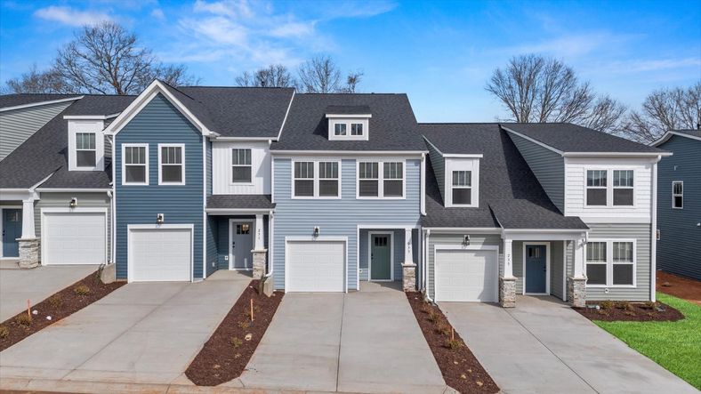Townhome with light blue exterior siding, seafoam green door, large windows, and two car driveway with one car garage