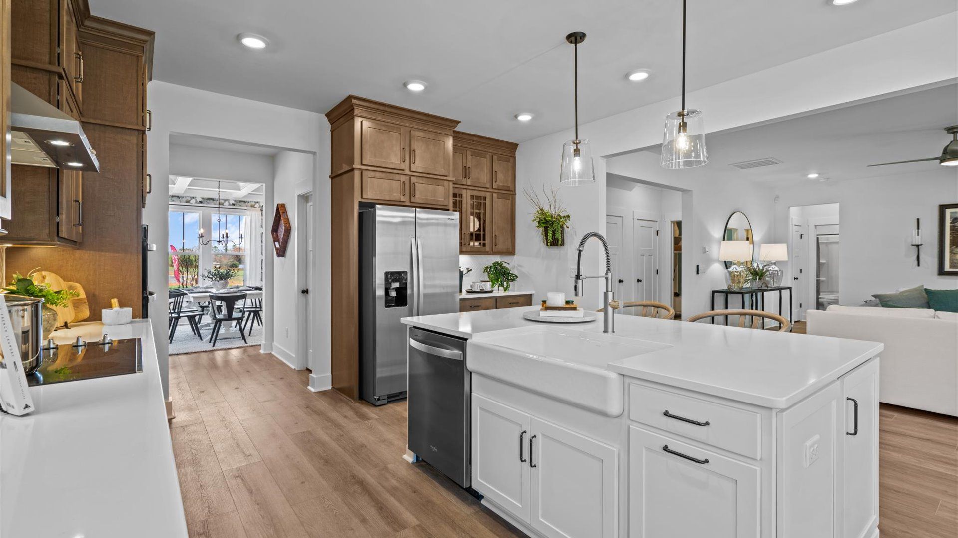 Open kitchen with built to ceiling wooden cabinets and long white island at Pinebrook by DRB Homes