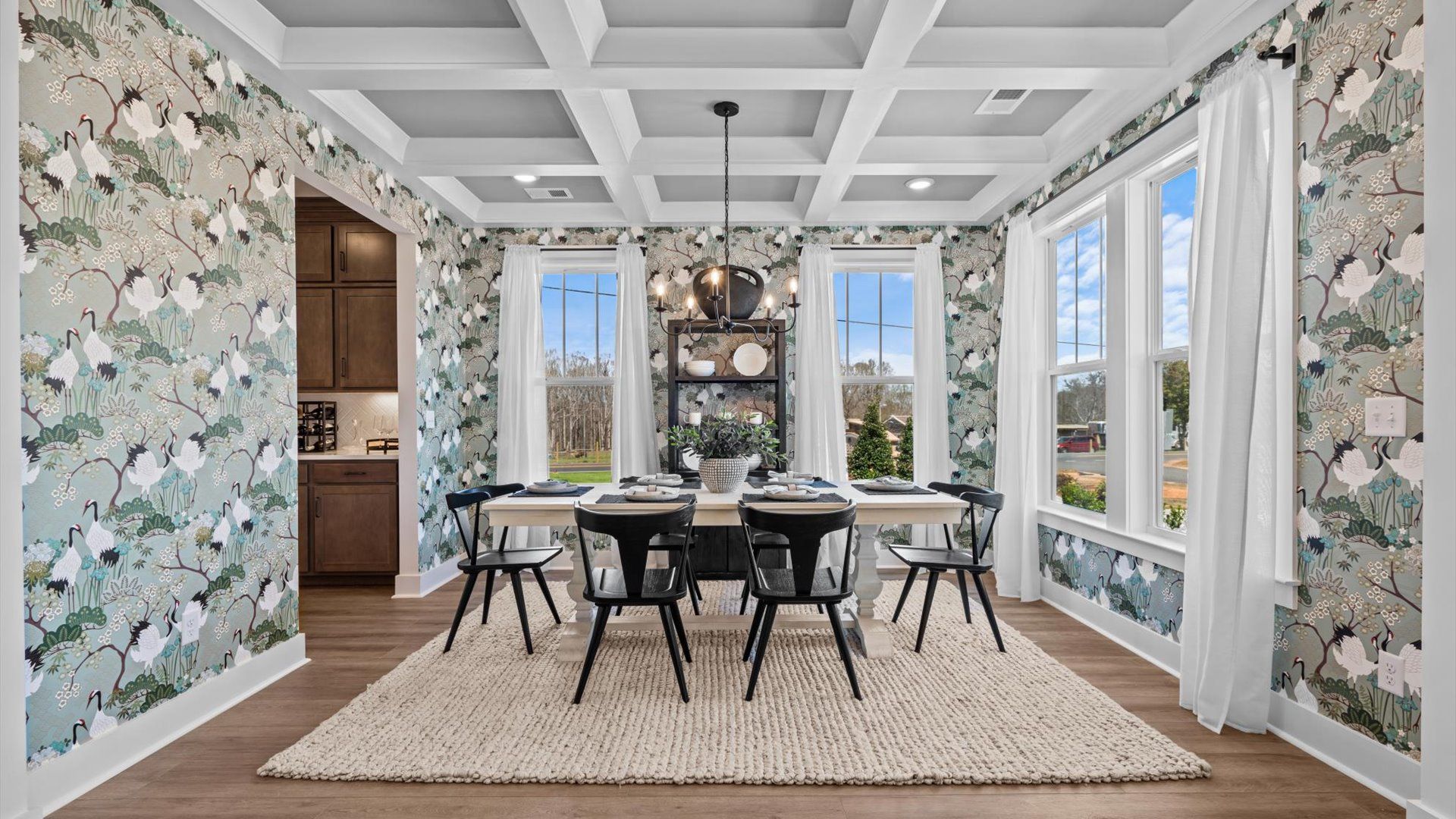 Coffered ceiling dining room with light blue accents and calming wallpaper at Pinebrook by DRB Homes in Woodruff, SC