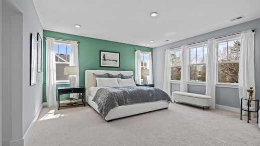 Large primary suite with large windows, plush carpet, and ceiling fan at Pinebrook by DRB Homes in Woodruff, SC