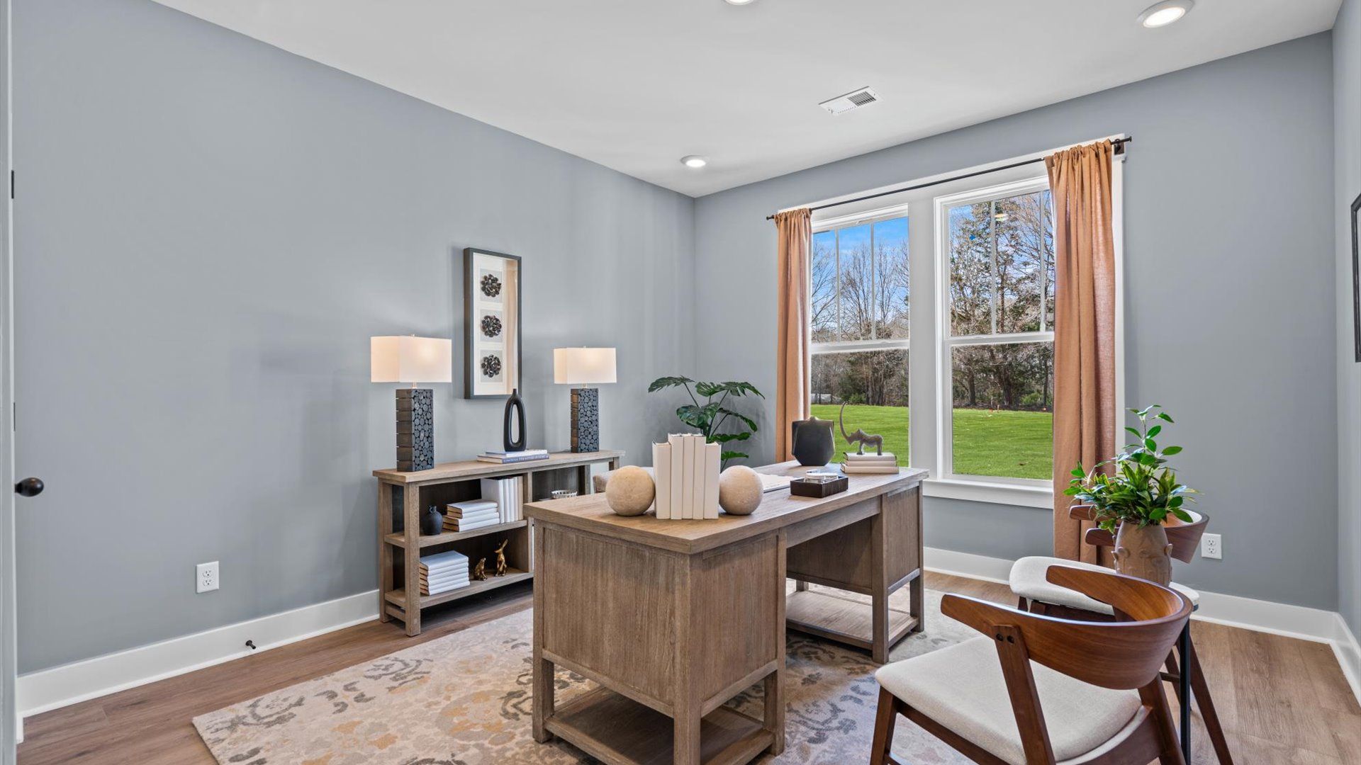 Hardwood flooring secondary bedroom staged as an office space with large windows at Pinebrook by DRB Homes in Woodruff, SC