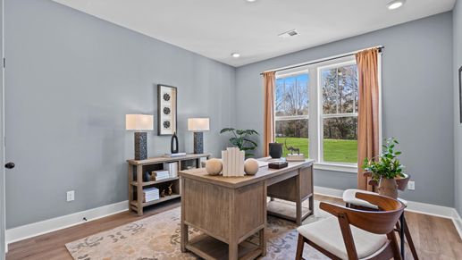 Hardwood flooring secondary bedroom staged as an office space with large windows at Pinebrook by DRB Homes in Woodruff, SC