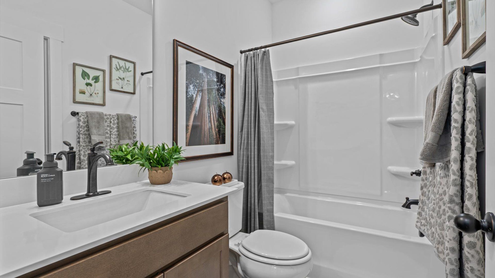 White quartz countertop vanity with wooden cabinetry in secondary bedroom at Pinebrook by DRB Homes in Woodruff, SC