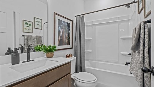 White quartz countertop vanity with wooden cabinetry in secondary bedroom at Pinebrook by DRB Homes in Woodruff, SC
