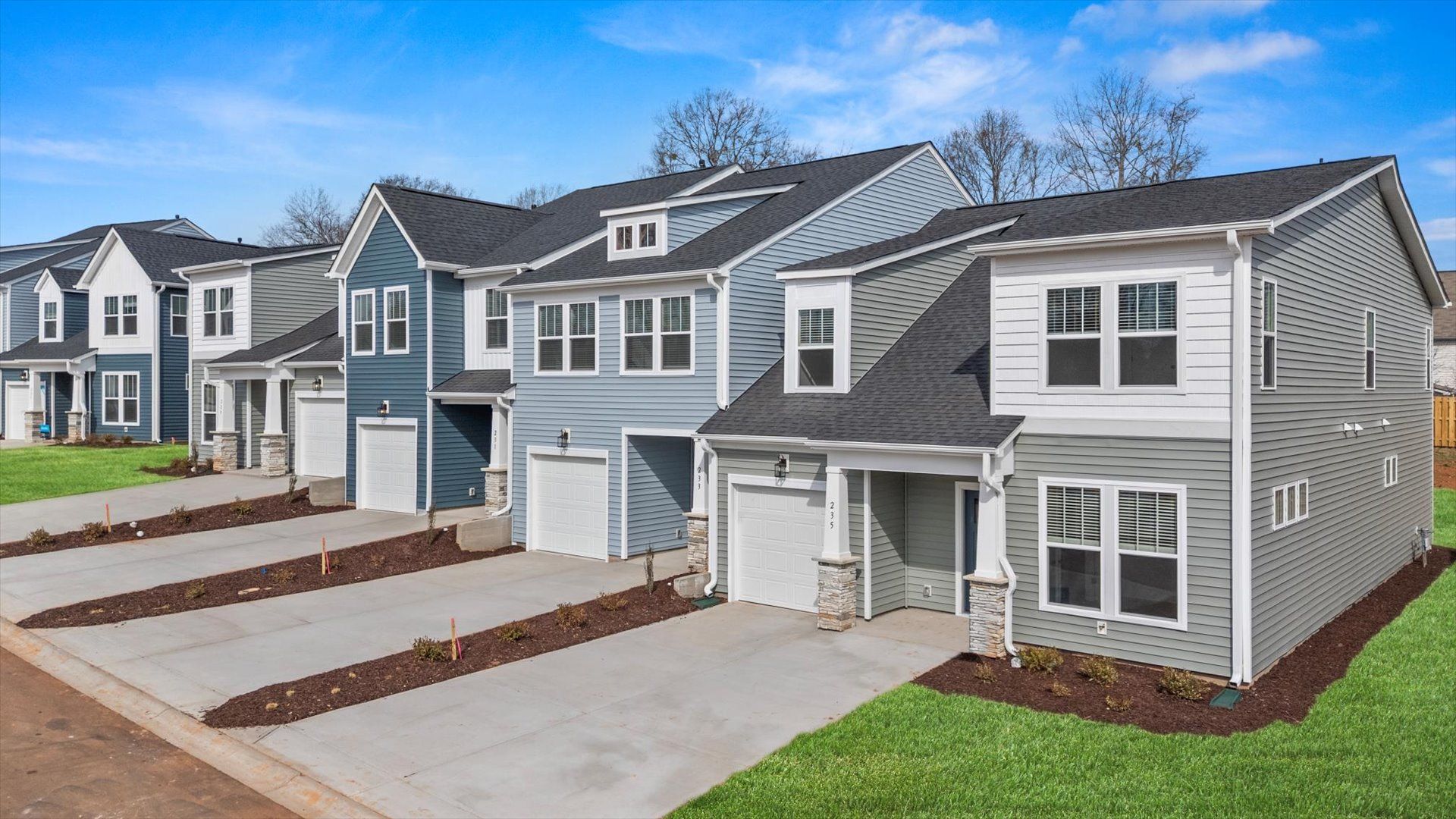Two story townhome with two car driveway, one car garage, and large windows with light blue exterior at Aspen Ridge