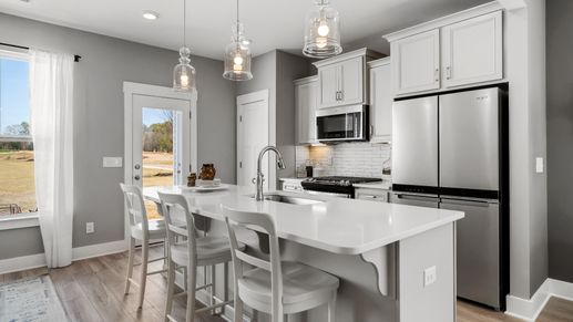 Kitchen with large island with white quartz countertops in two story townhome at Saluda Crossing by DRB Homes in Piedmont, SC