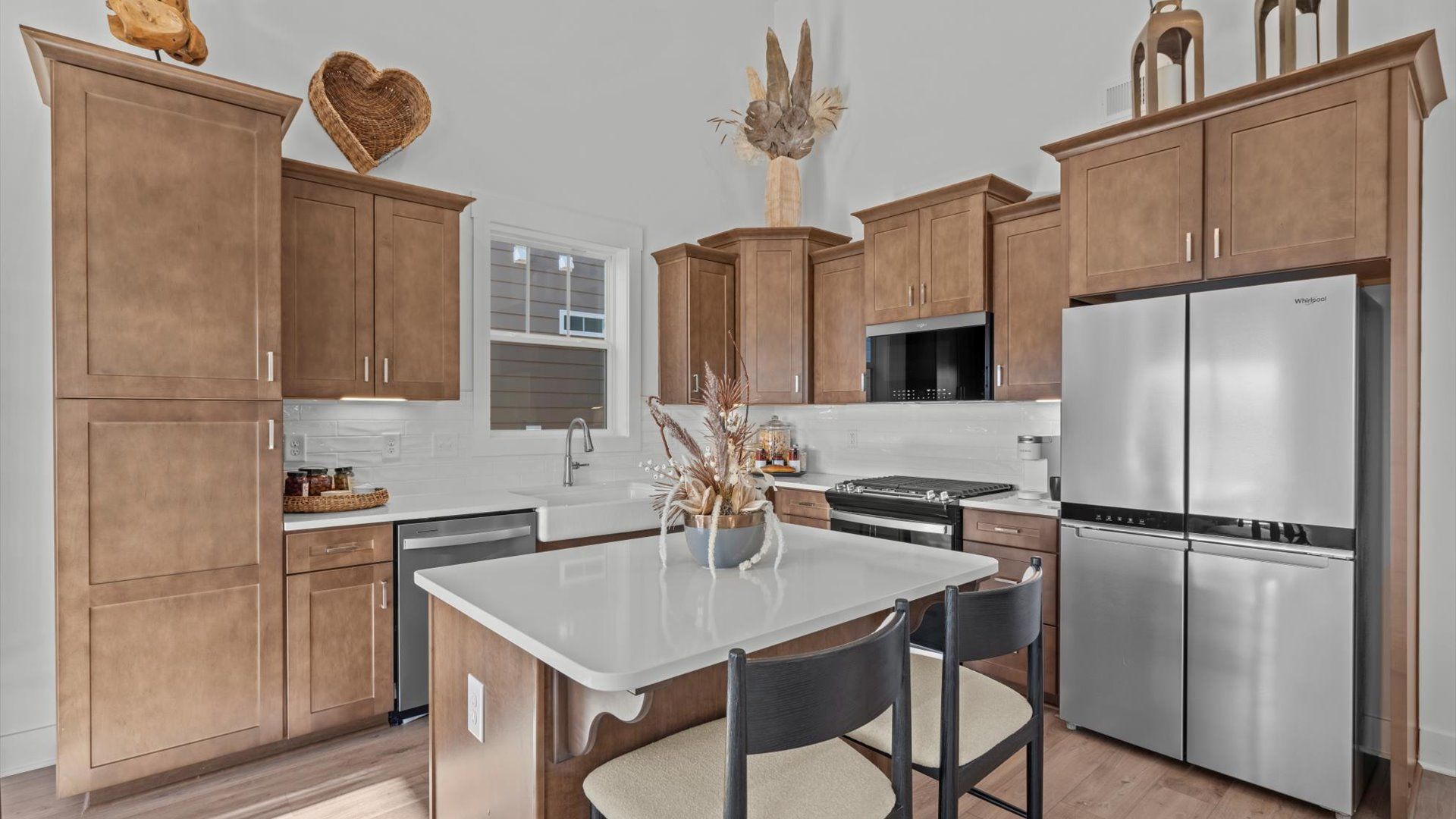Two story ceiling kitchen with wooden cabinets and white quartz countertops at Mulberry Estates by DRB Homes
