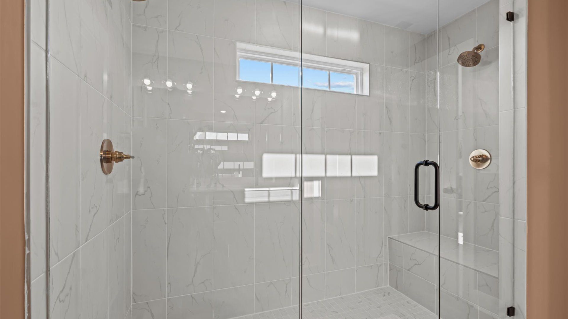 Stunning marble tiled walk-in shower with bench seat and frameless door at Mulberry Estates by DRB Homes in Simpsonville, SC