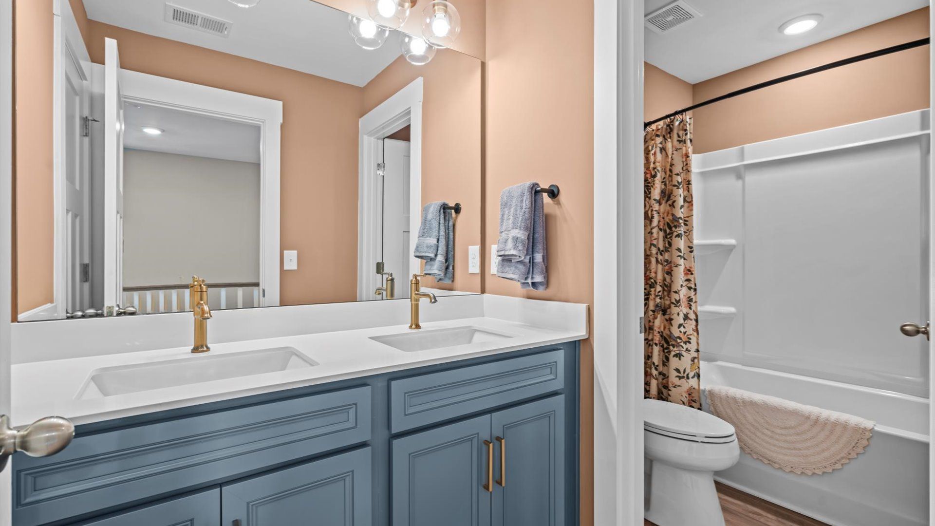 Blue cabinetry secondary bathroom with gold accents in two story home at Mulberry Estates by DRB Homes in Simpsonville, SC