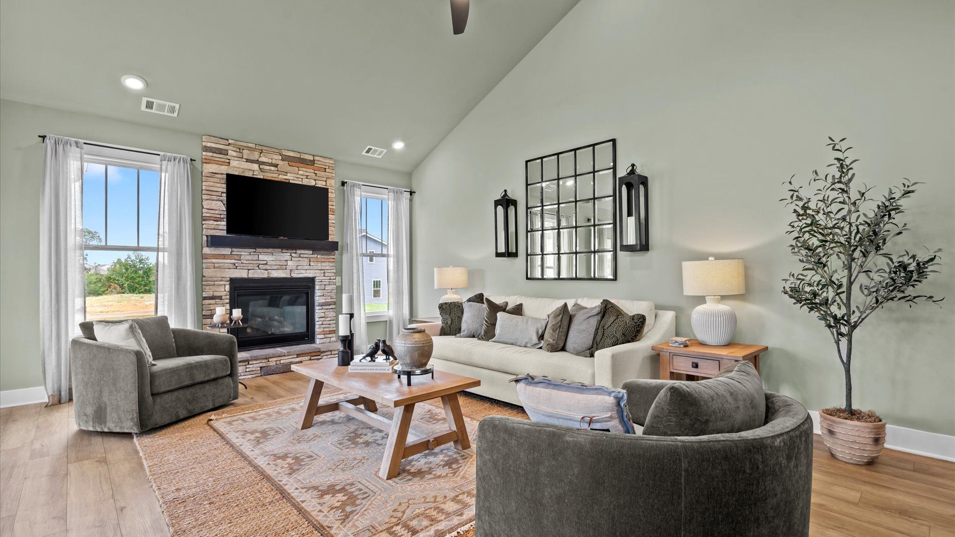 Family room with tall vaulted ceilings, hardwood flooring, and stone fireplace in two story home at DRB Homes in Easley, SC