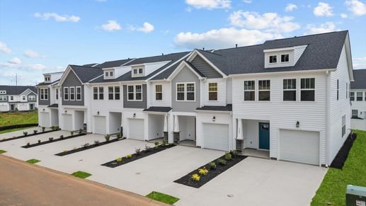 Townhome with white and grey exteriors and a two-car parking pad in Greenville, SC at Hickory Heights by DRB Homes