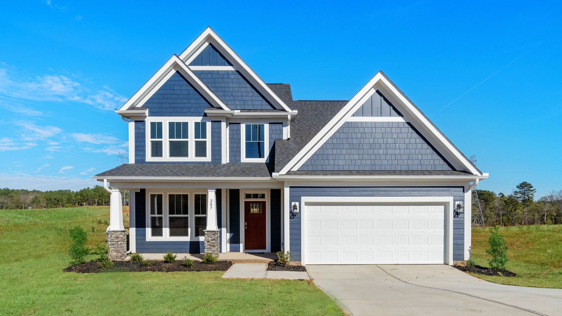 Vibrant two-story home with navy exterior, stone finishes, a dark red door, and a two-car garage located in Woodruff, SC