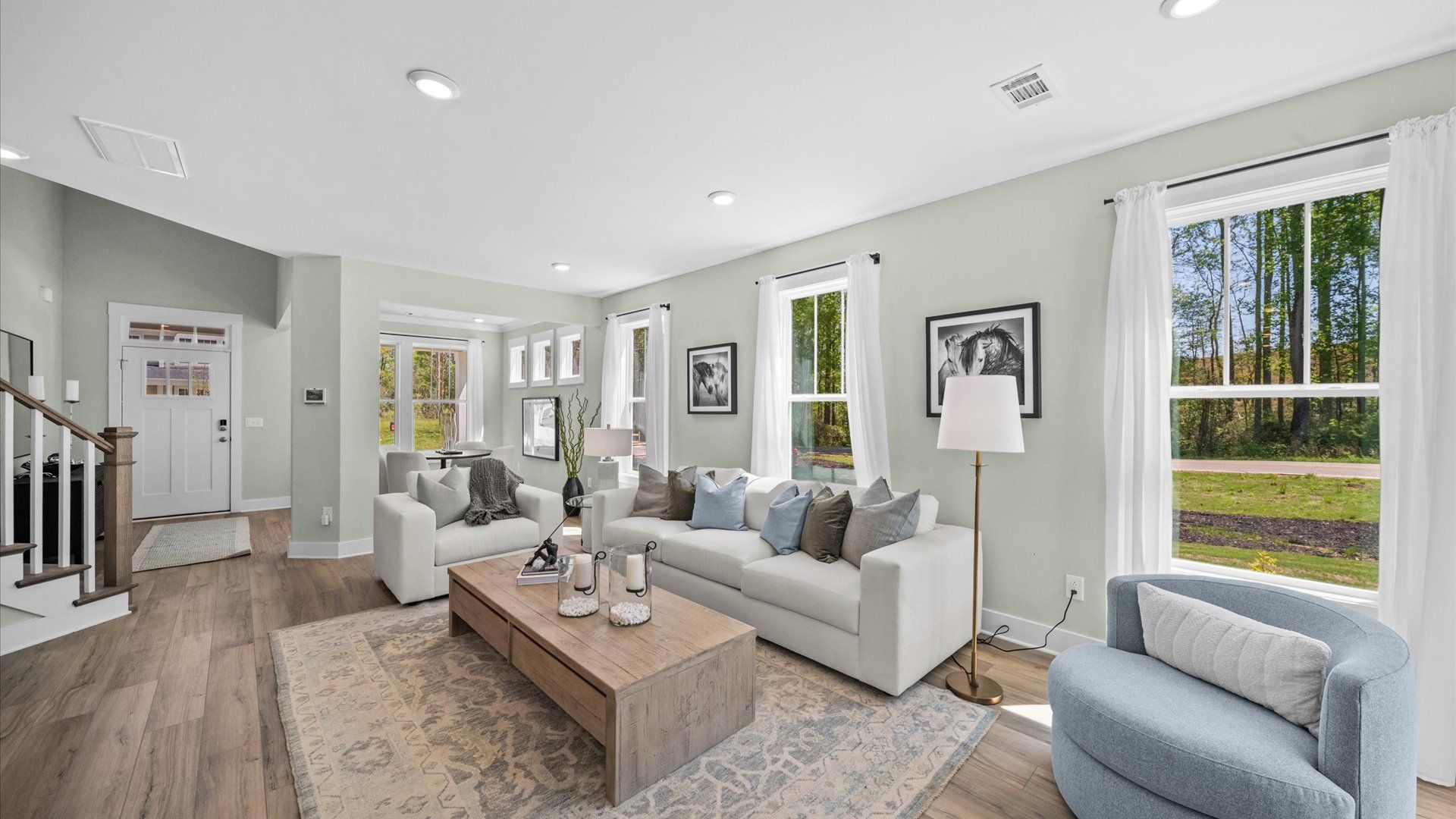 Spacious family room with light green walls, hardwood floors, and light blue and grey decor at Harrier Point in Woodruff, SC