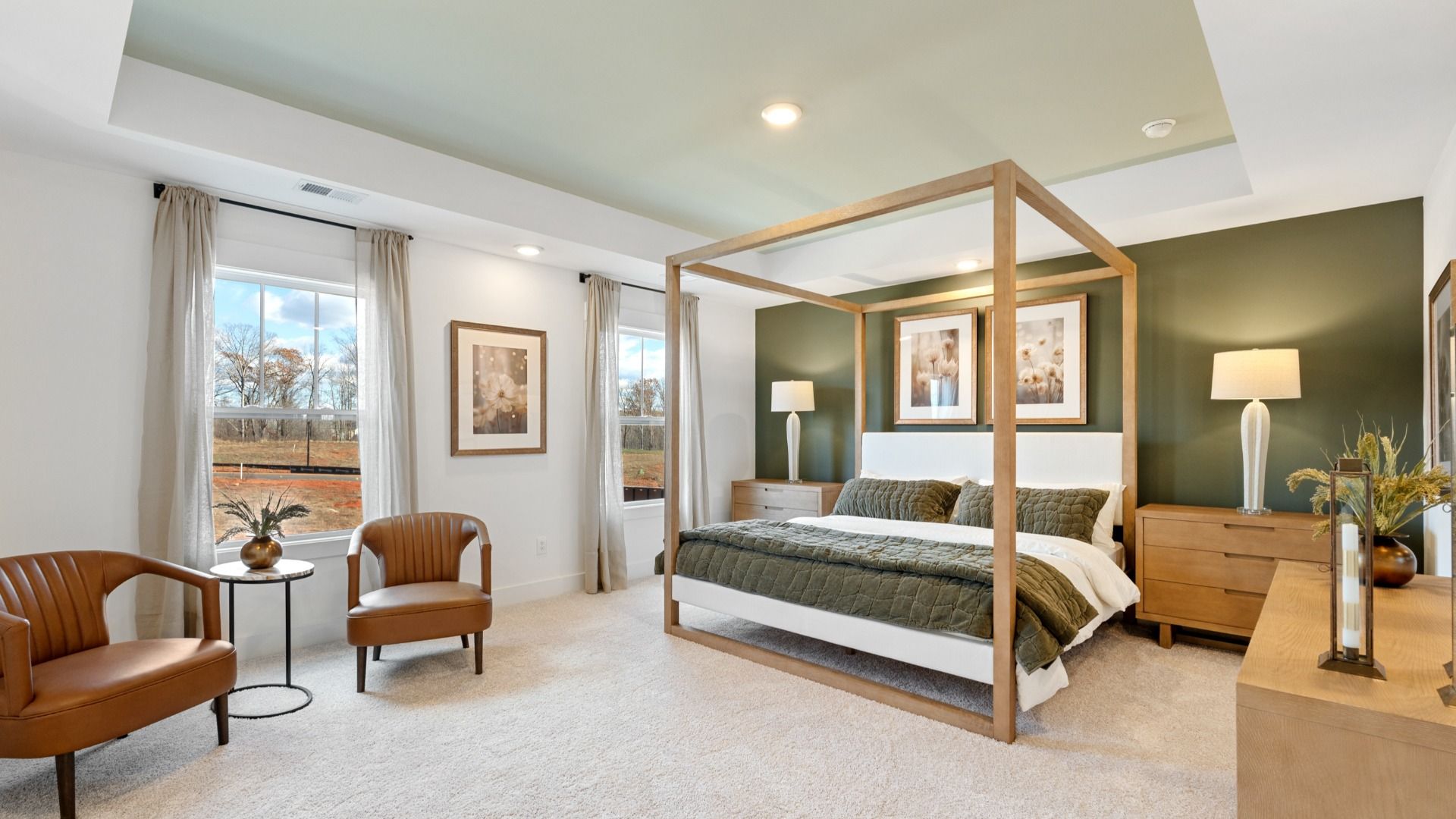 Large primary suite with green accent wall, carpeted floors, eye-catching details, and tray ceilings at Harrier Point
