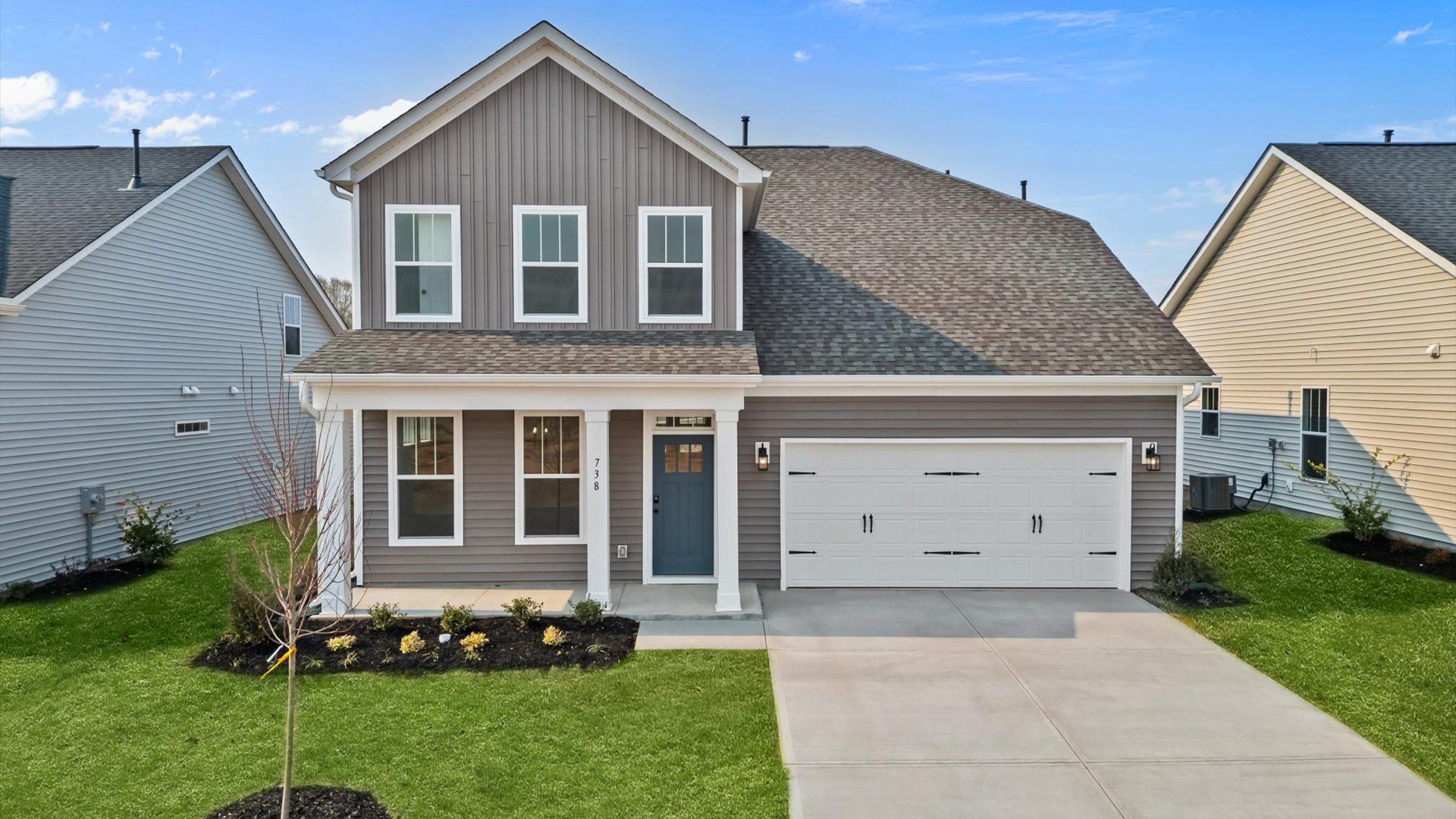 Memorable first impression two-story home with light brown exterior, covered front porch, and two-car garage in Woodruff, SC