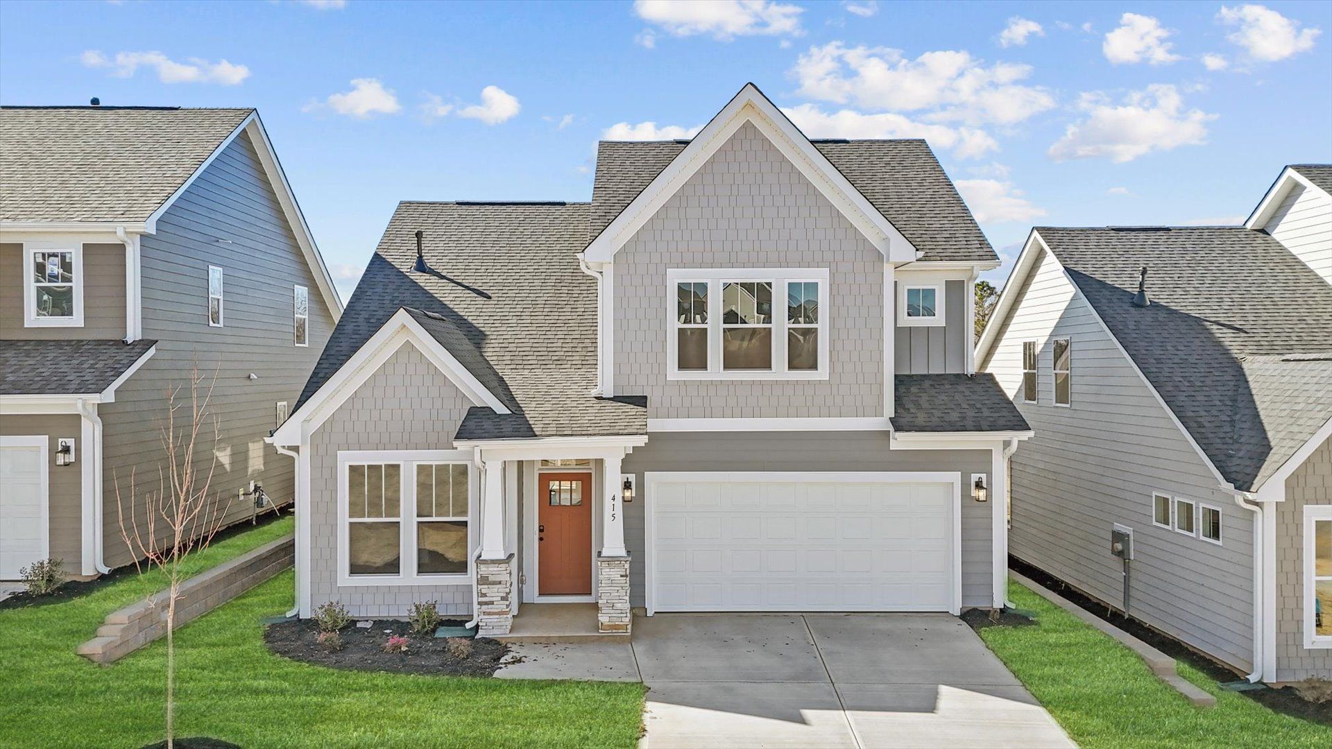 Finley floorplan with neutral exterior and stone columns at The Reserve at Livingston Park by DRB Homes in Easley, SC