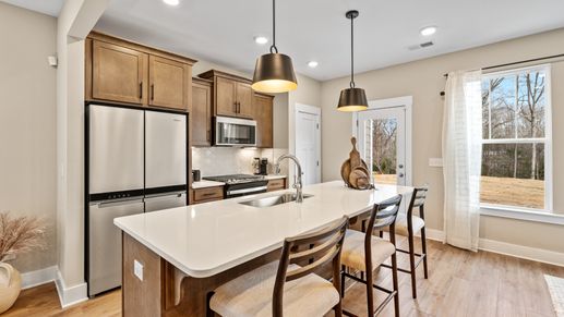 Spacious, cozy, modern kitchen with wooden cabinetry and large windows at Hickory Heights by DRB Homes