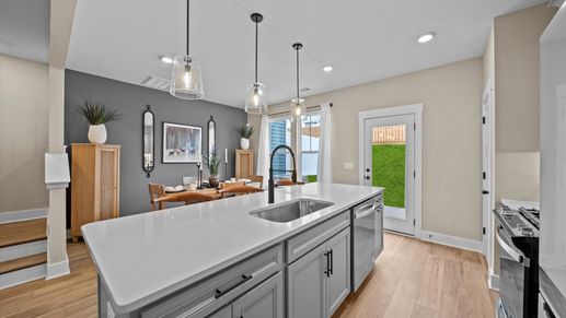 Open concept gray accented kitchen with white quartz countertop large island with counterstools at Aspen Ridge by DRB Homes