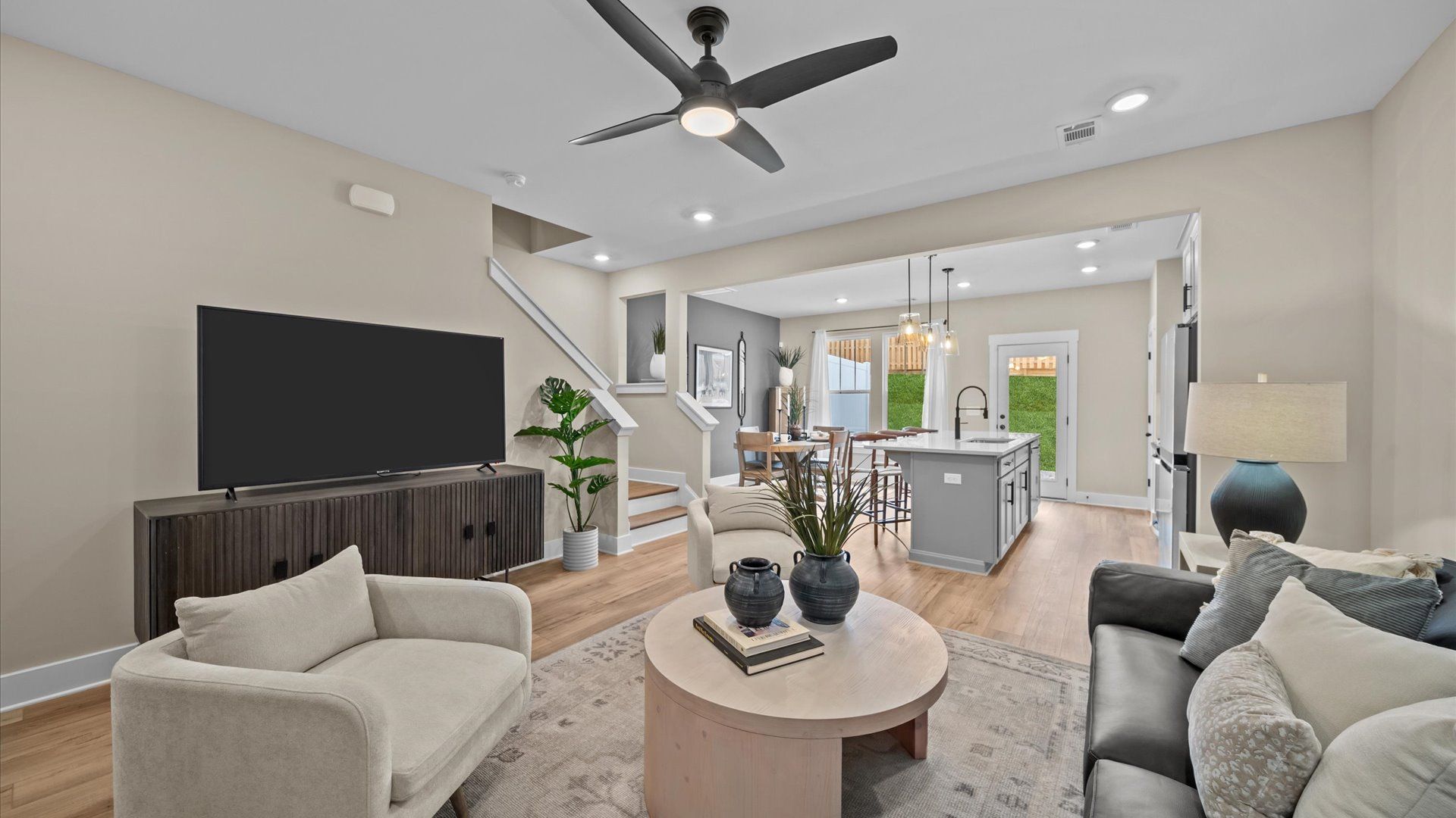 Spacious family room with large windows, yard access, hardwood flooring, and ceiling fan with elevated ceilings