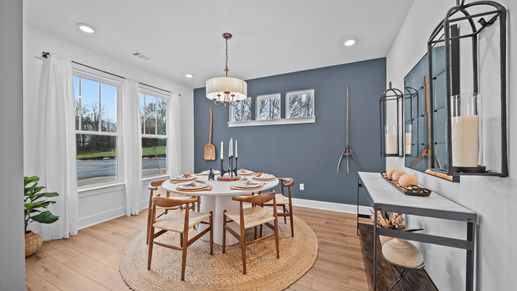 Inviting, spacious dining room with large windows, hardwood flooring, chandelier, and elevated ceilings