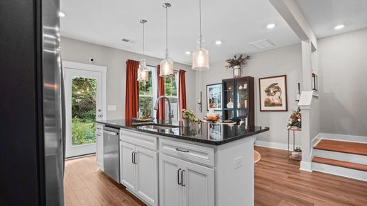 Black and white modern kitchen with granite countertops and tiled backsplash at Clayton Crossing by DRB Homes in Arden, NC