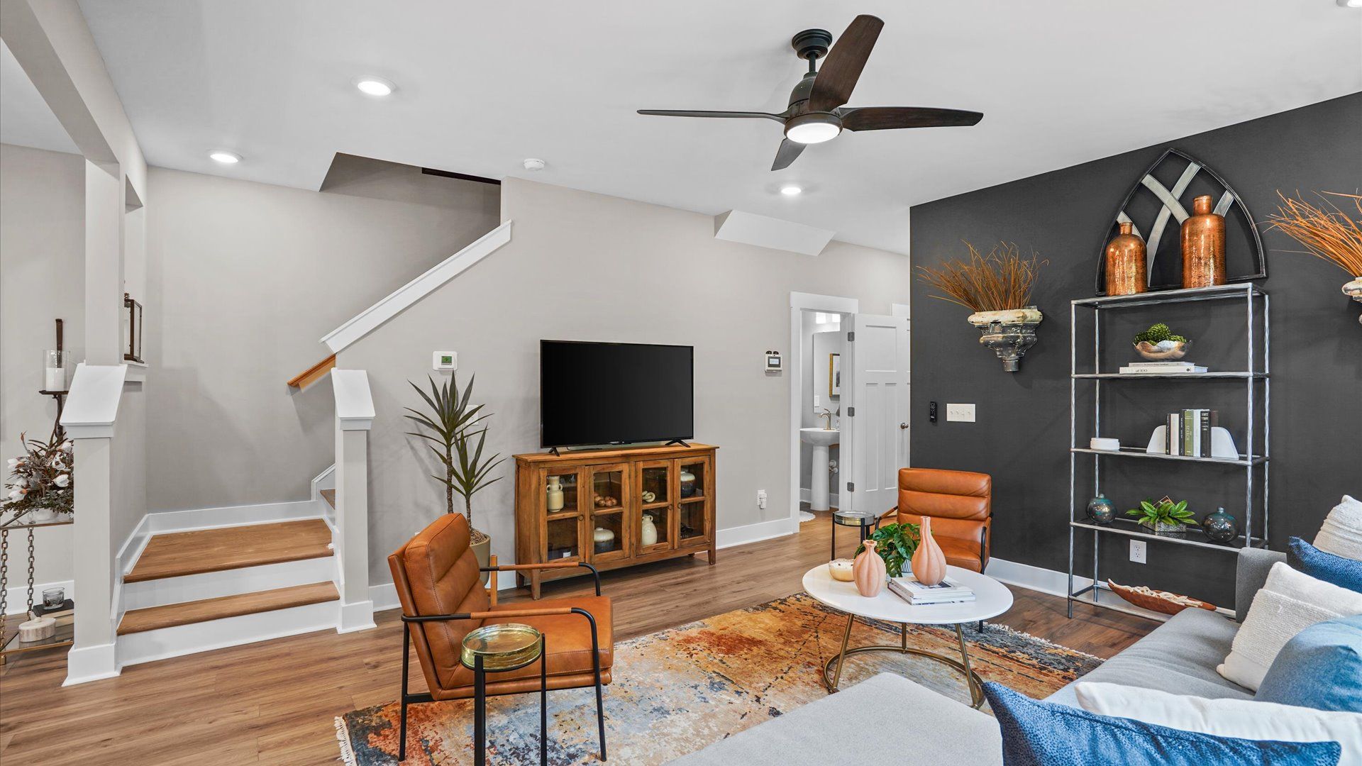 Colorful, modern family room with hardwood flooring, large windows, and elevated ceilings with ceiling fan in Arden, NC