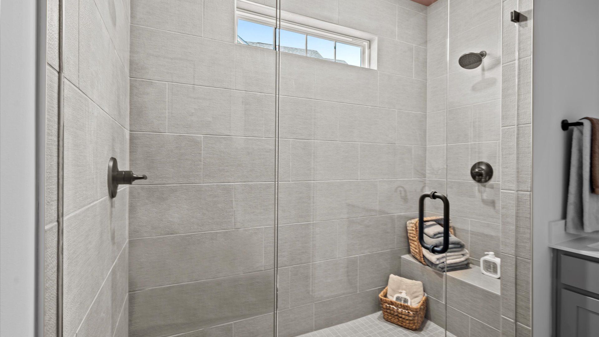 Notable primary bath featuring frameless tiled walk-in shower and tasteful design touches throughout