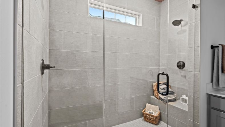 Notable primary bath featuring frameless tiled walk-in shower and tasteful design touches throughout