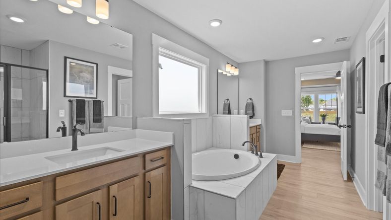 Notable primary bath featuring separate vanities, soaking tub, and tasteful design touches throughout