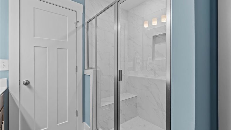 Luxe tiled walk-in shower with bench seat in two story townhome at Ransdell Pointe by DRB Homes in Spartanburg, SC