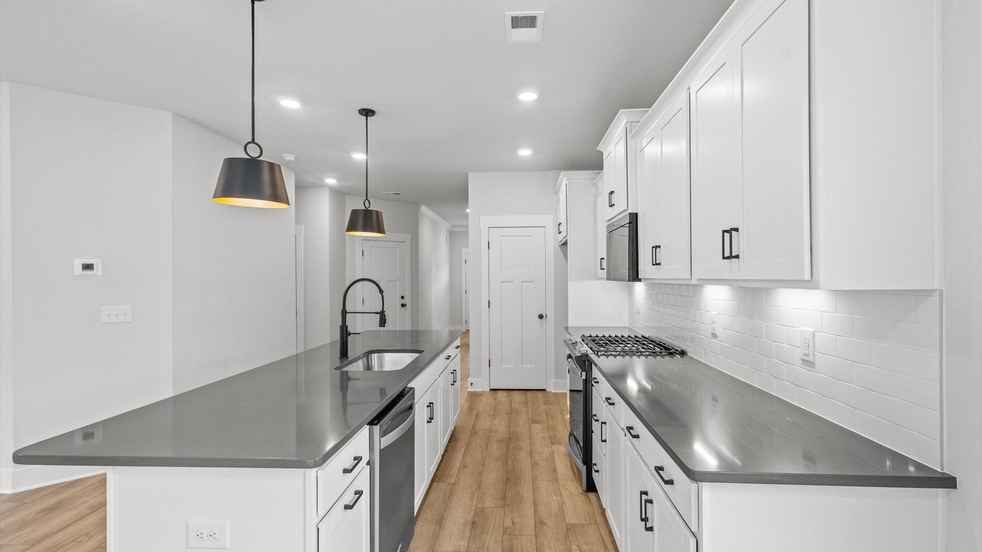 Neroli home plan open concept kitchen with large central island, tile backsplash and ample counter/cabinet space