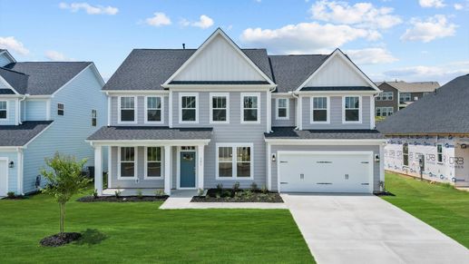 Gray exterior Stonefield floorplan two story home with blue door and two car garage at Wells Crossing by DRB Homes