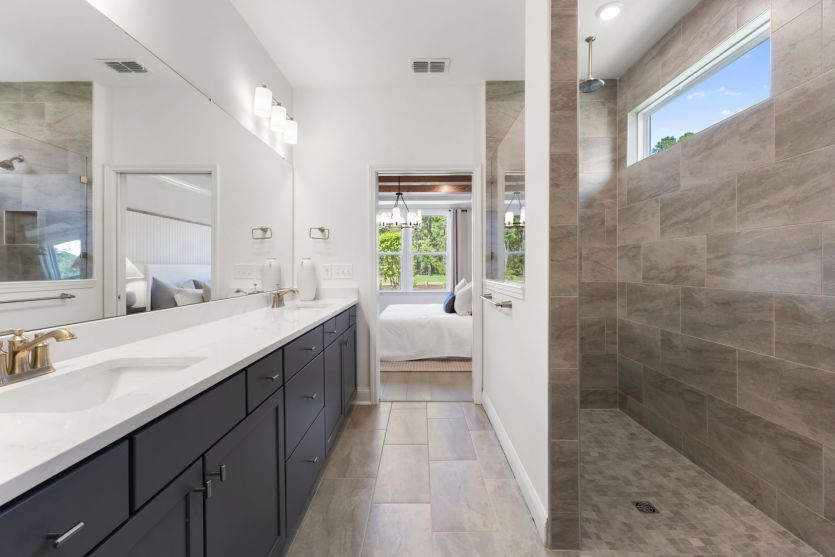 Owner's bathroom with a frameless walk-in shower and dual sink vanity.