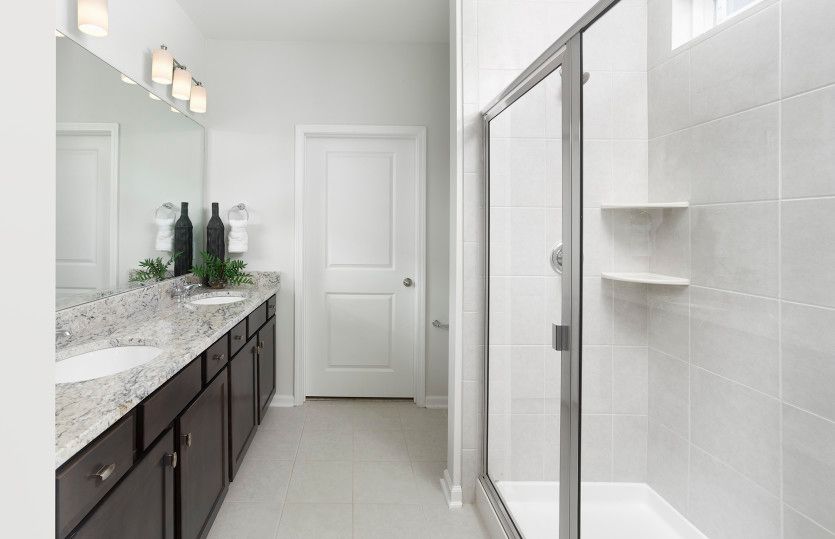 Elegant Owner's Bath with a tile walk-in shower and spacious dual vanity. Model Representation.