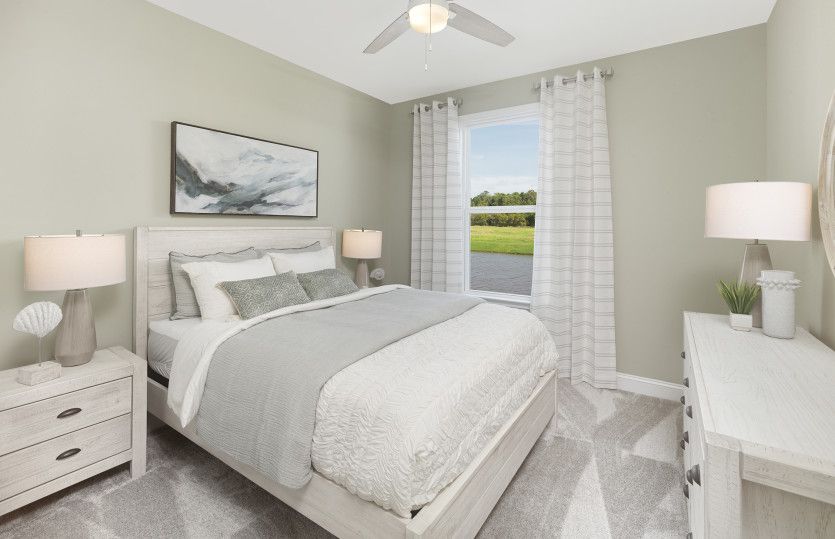 Spacious secondary bedroom with plush carpet and a large window to capture the soft natural light. M