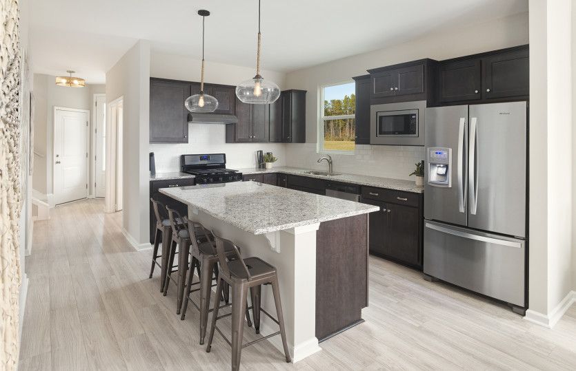Modern kitchen with stainless steel appliances and bright pendant lighting.