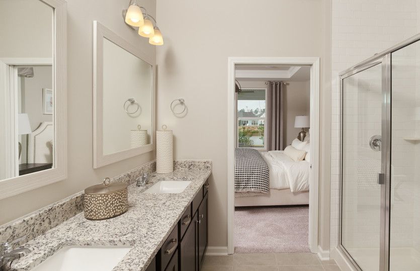 Owner's suite bath with walk-in tile shower and dual vanities.