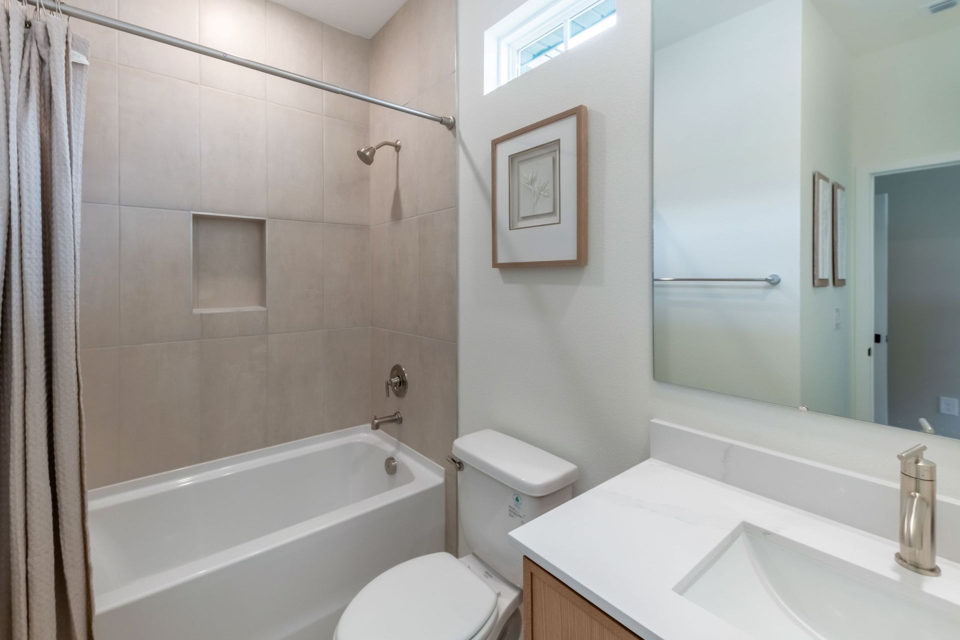 A bright and modern secondary bathroom featuring sleek finishes and a spacious vanity—perfect for guests or family.