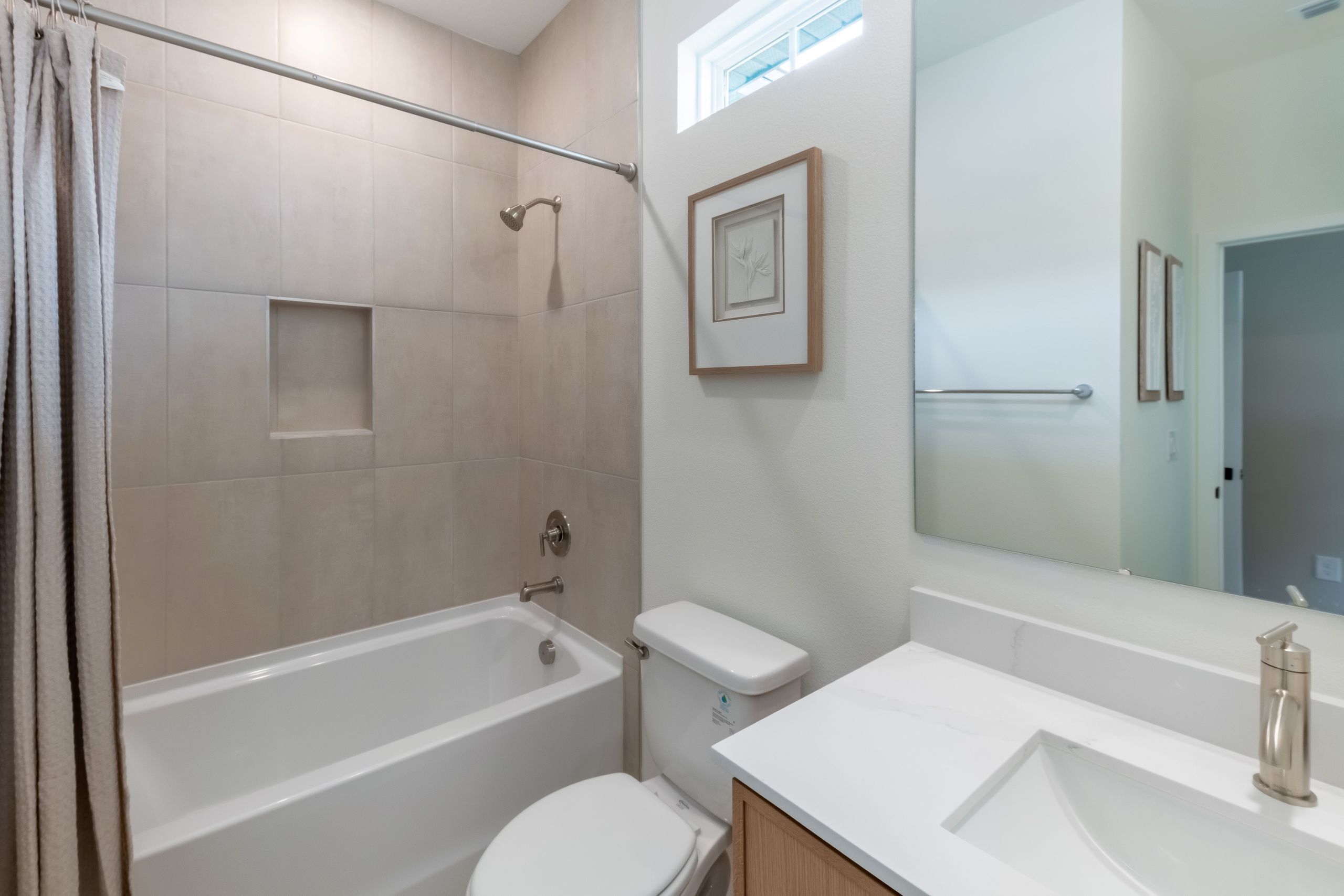 A bright and modern secondary bathroom featuring sleek finishes and a spacious vanity—perfect for guests or family.