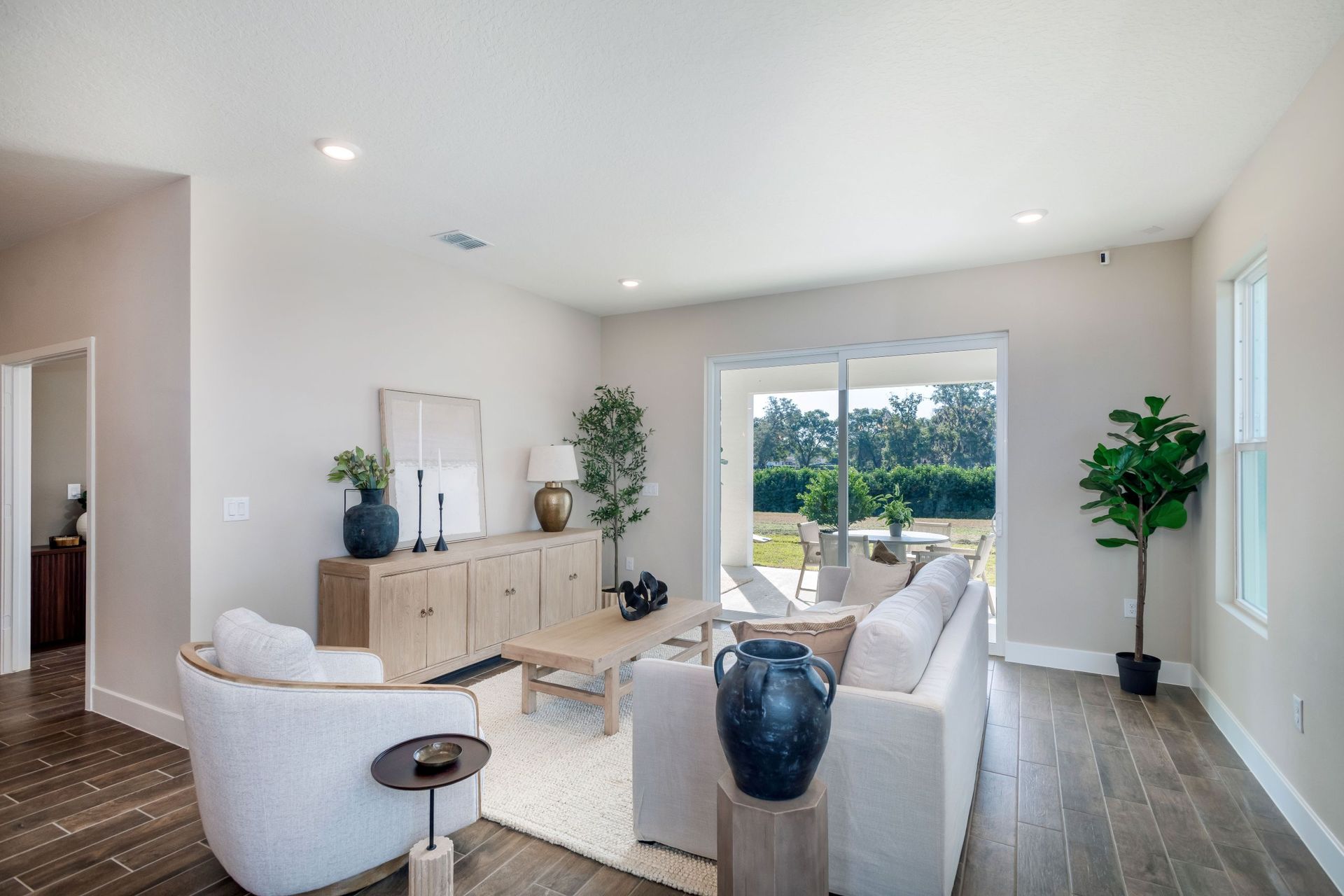 A bright and inviting great room featuring modern finishes, warm natural light, and seamless indoor-outdoor living with large sliding doors that open to the covered lanai.