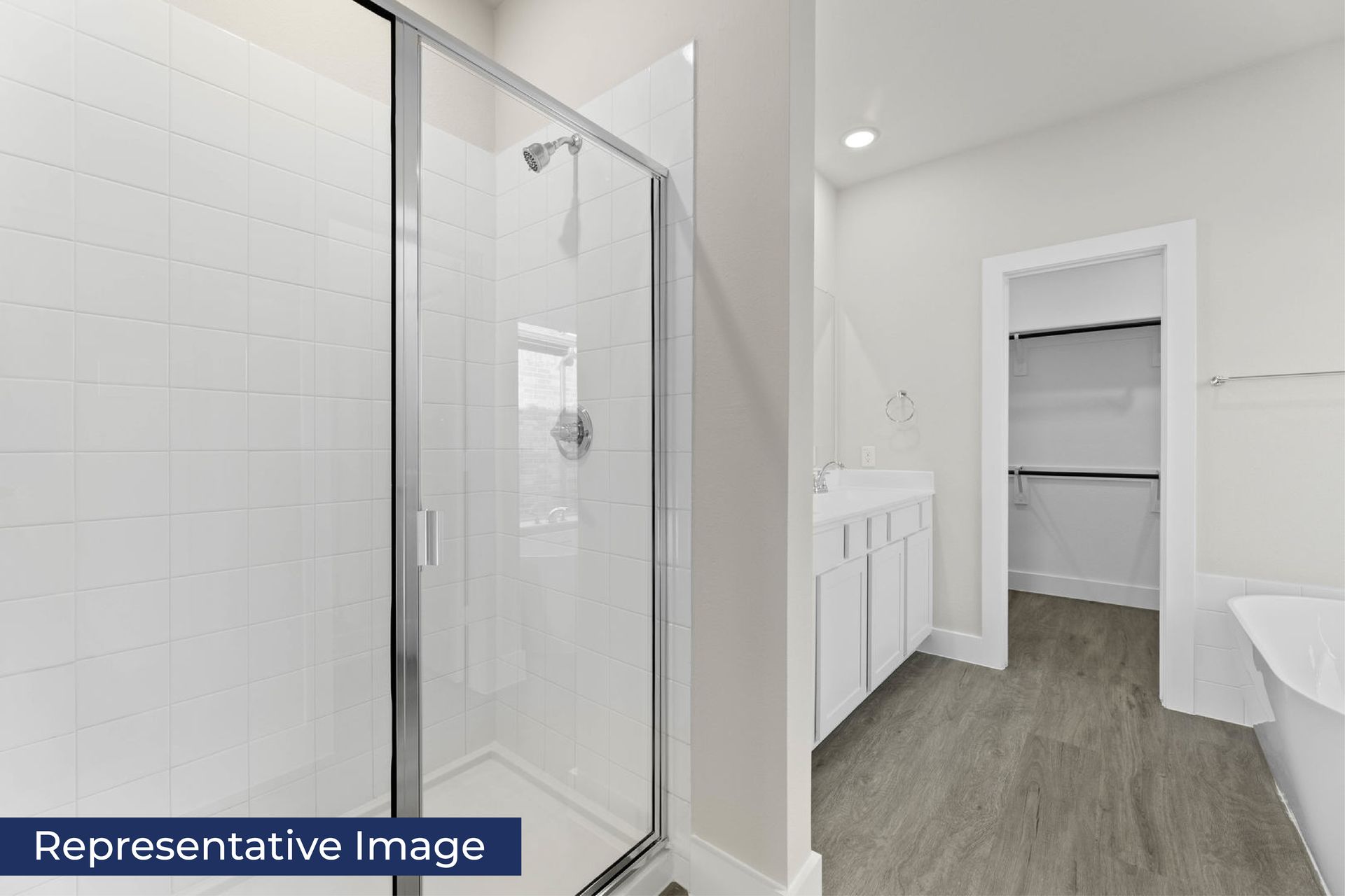 Modern bathroom with glass shower, vanity, and walk-in closet.