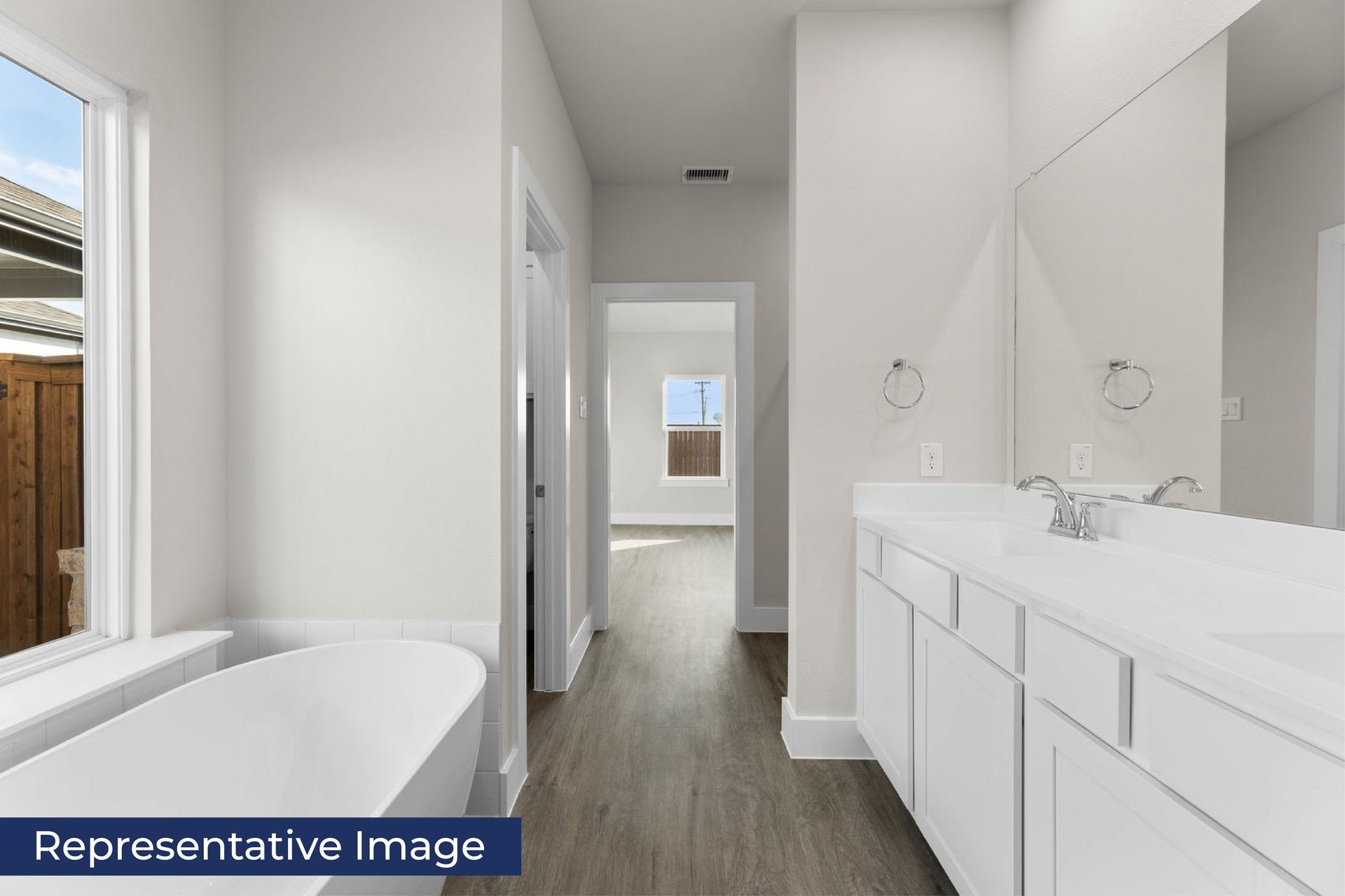 Modern bathroom with bathtub, double sink, and wooden flooring.