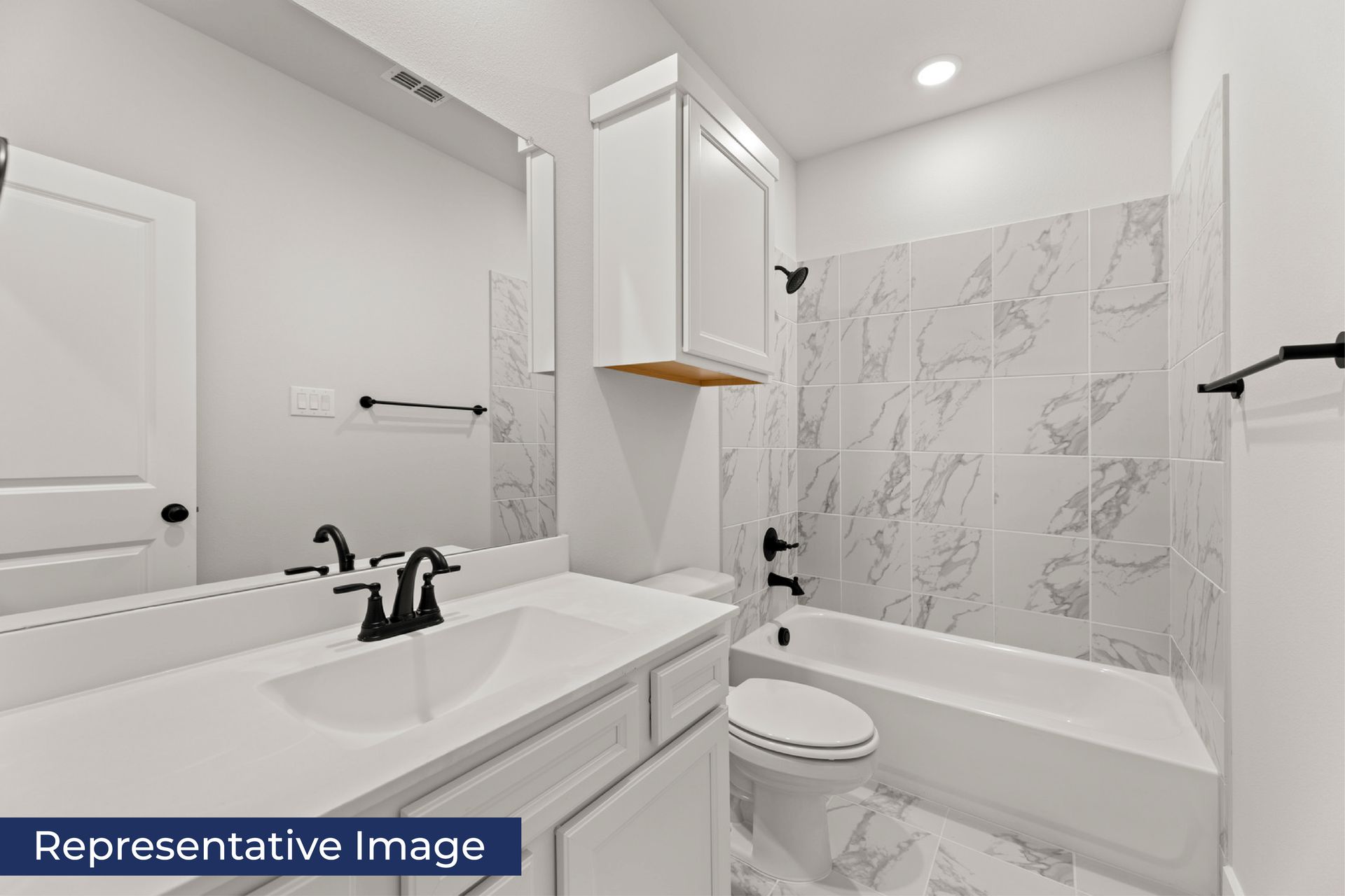 Modern bathroom with marble tile and white fixtures.