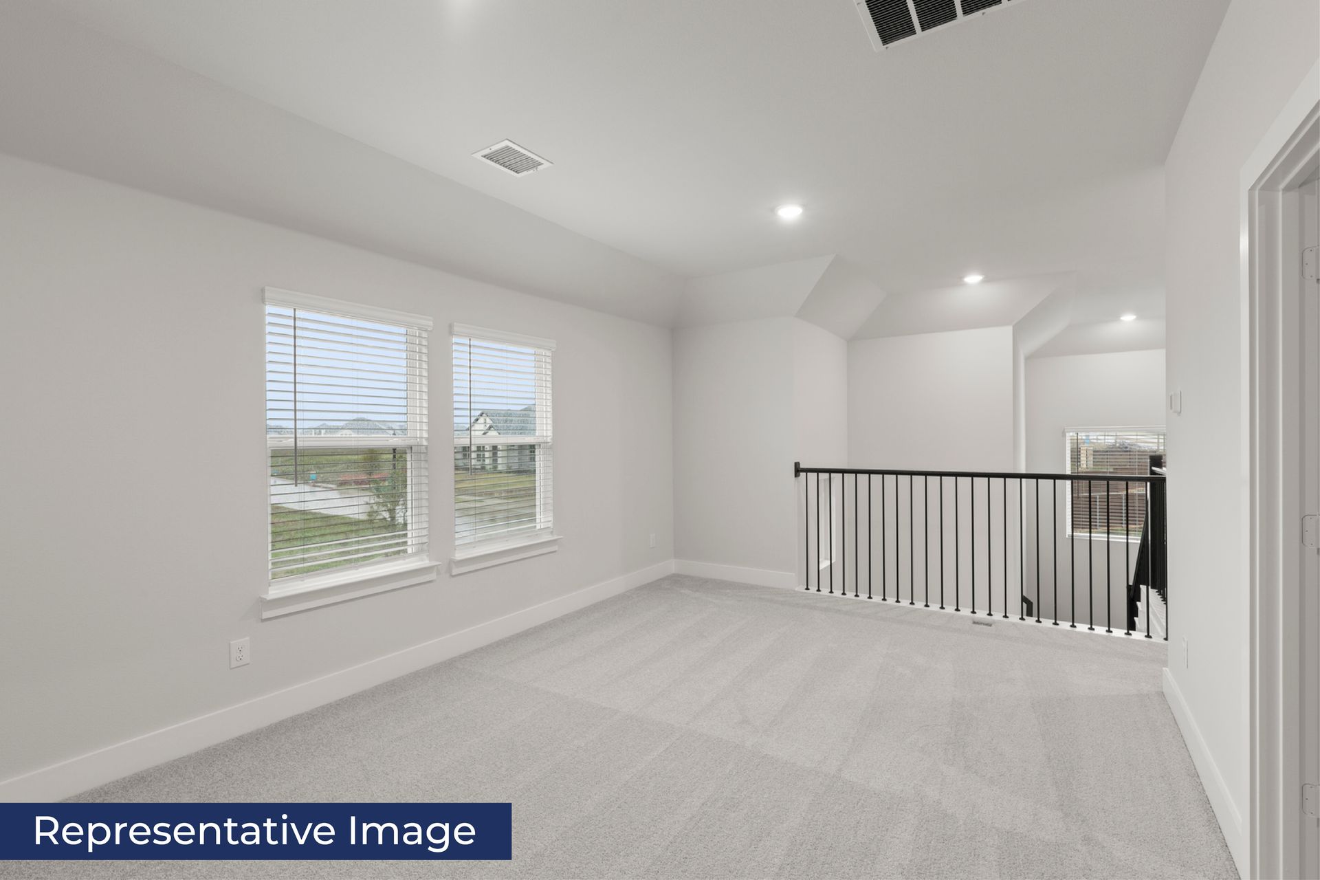 Bright upstairs loft area with windows and carpet flooring.